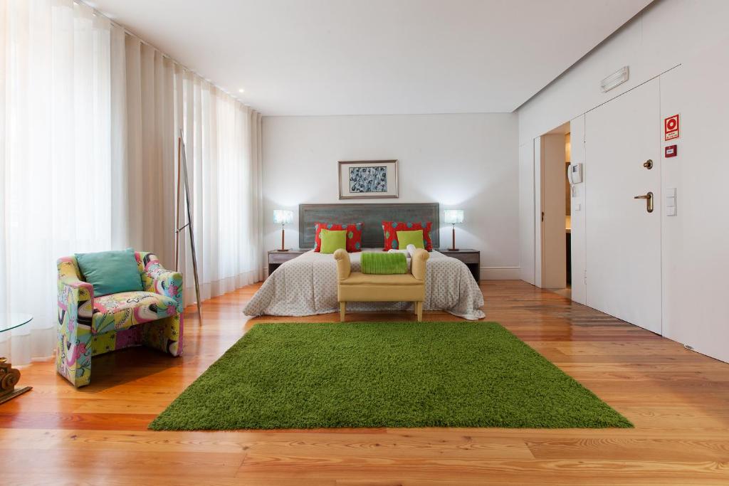 a living room with a green rug and a bedroom at Capim Dourado Apartments Cedofeita in Porto