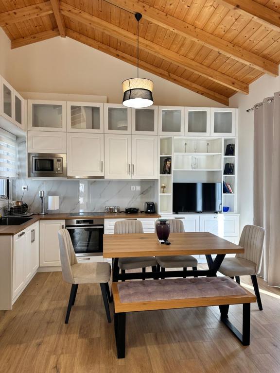 a kitchen with white cabinets and a wooden table and chairs at Nōema Residences I in Nafpaktos
