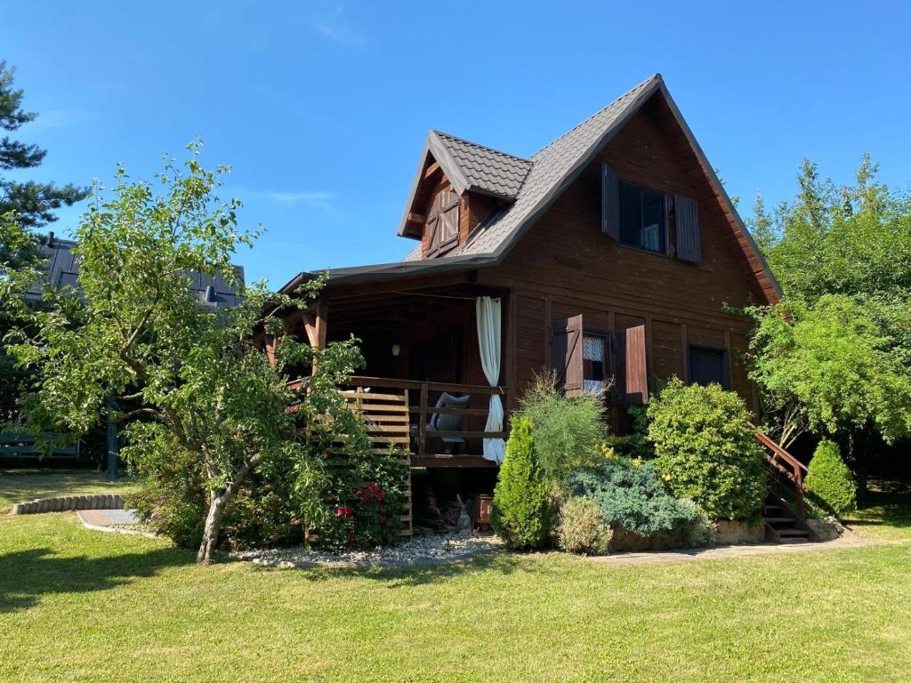 a wooden house with a porch in a yard at Domek letniskowy Fuleda in Fuleda