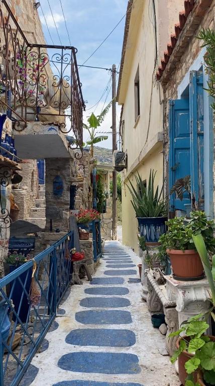 a stone alley with blue doors and plants in a village at Blue Street Apartments in Pythagoreio