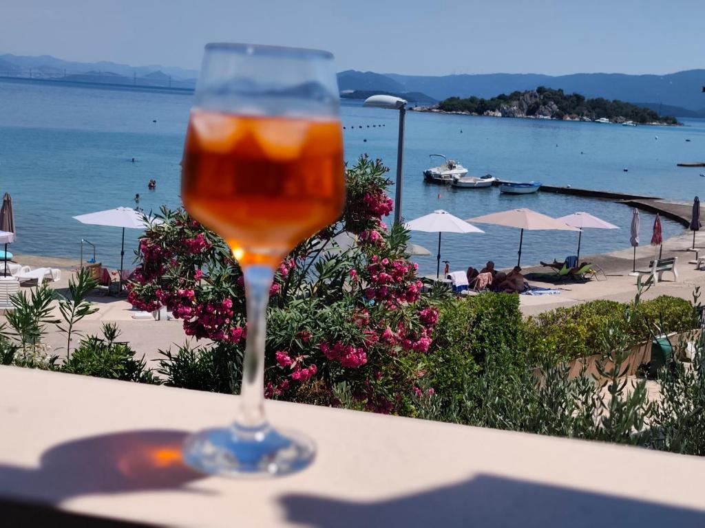 a glass of beer sitting on a table next to a beach at Ema & Jakov in Sreser