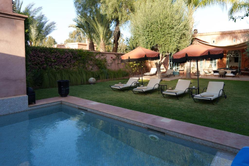 a swimming pool with chairs and umbrellas in a yard at Villa Riad Marrakech in Najem