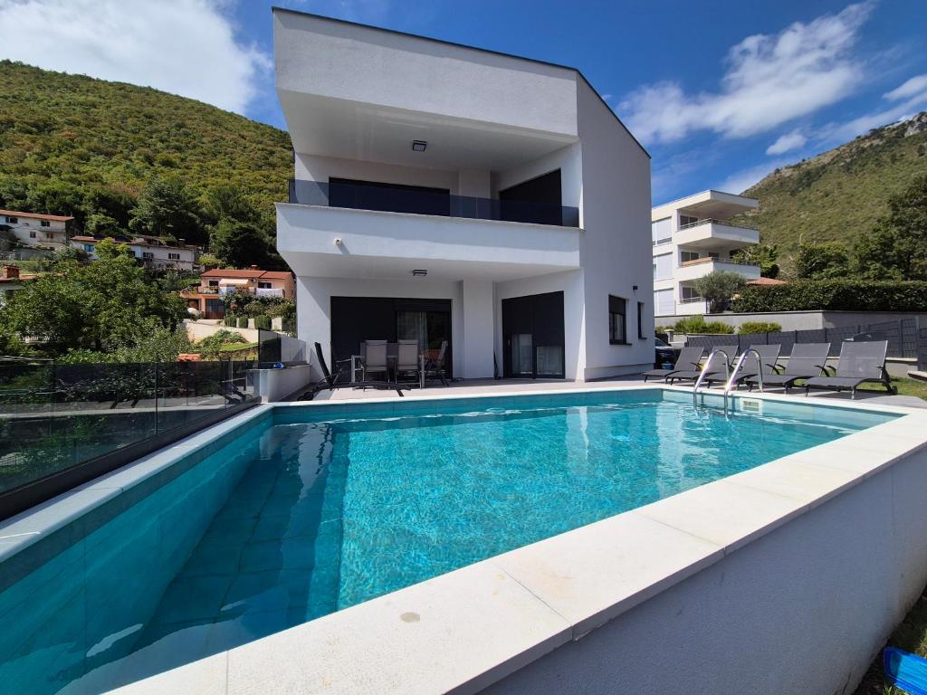 a villa with a swimming pool in front of a house at Villa Aylen in Mošćenička Draga