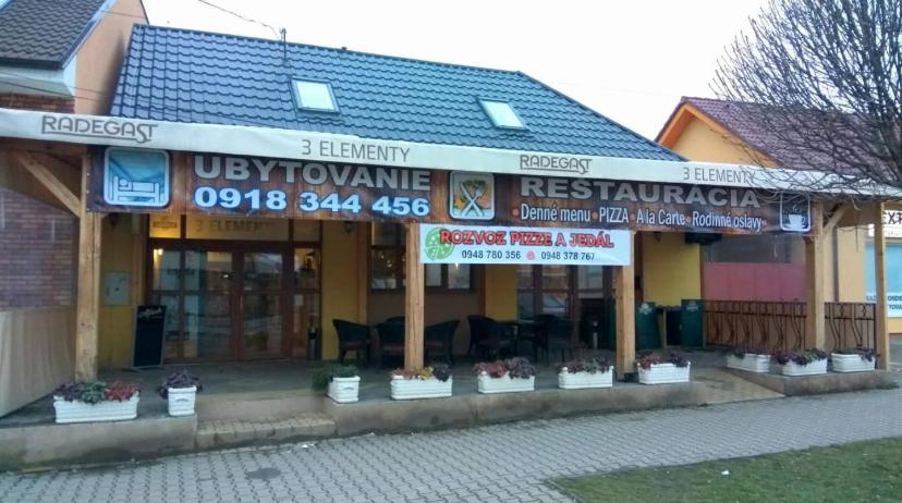 a restaurant with signs on the front of a building at 3 Elementy in Čachtice