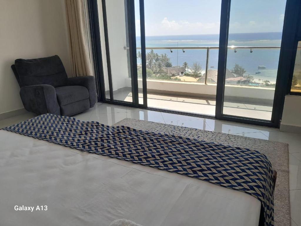 a bedroom with a bed and a chair and a large window at Seaview homestay on Third avenue beach apt- nyali in Mombasa