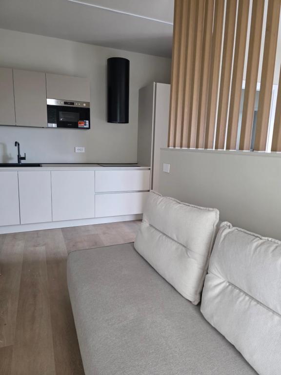 a living room with a white couch and a kitchen at EMERALD Suites Cervia in Cervia