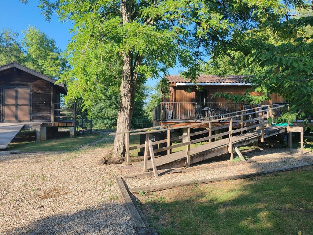 a wooden cabin with a fence and a tree at Le chalet Campy in Moustier