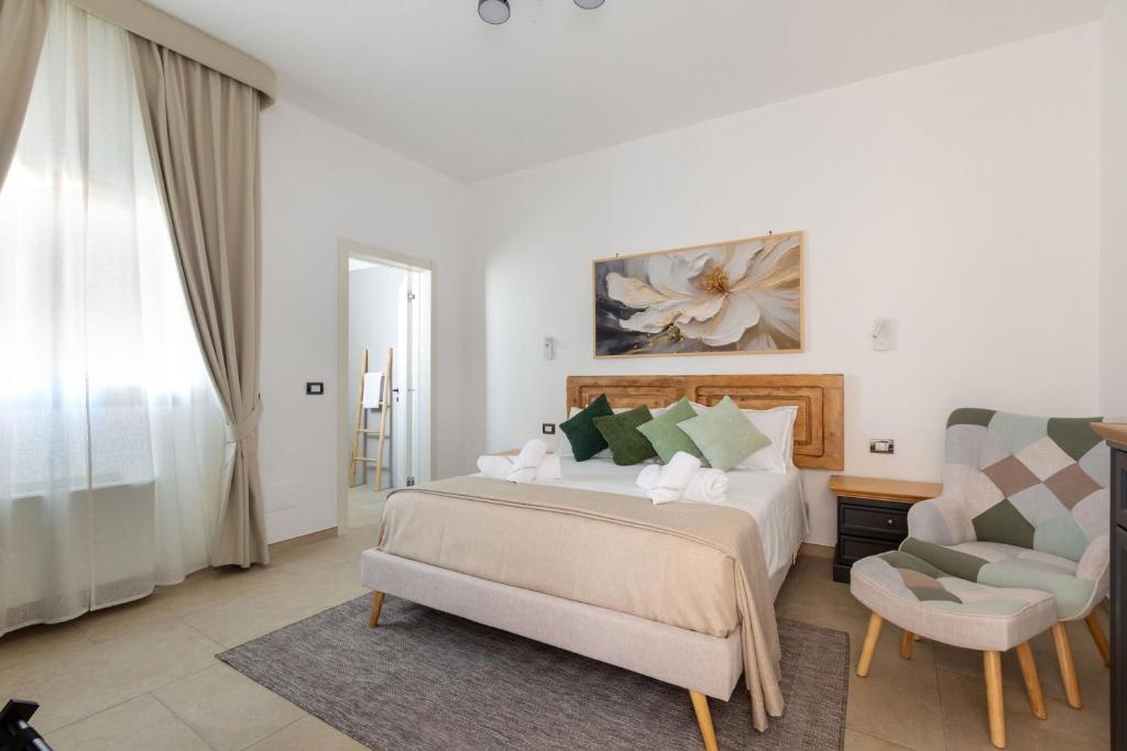 a white bedroom with a bed and a chair at Domus Sagari in Presicce