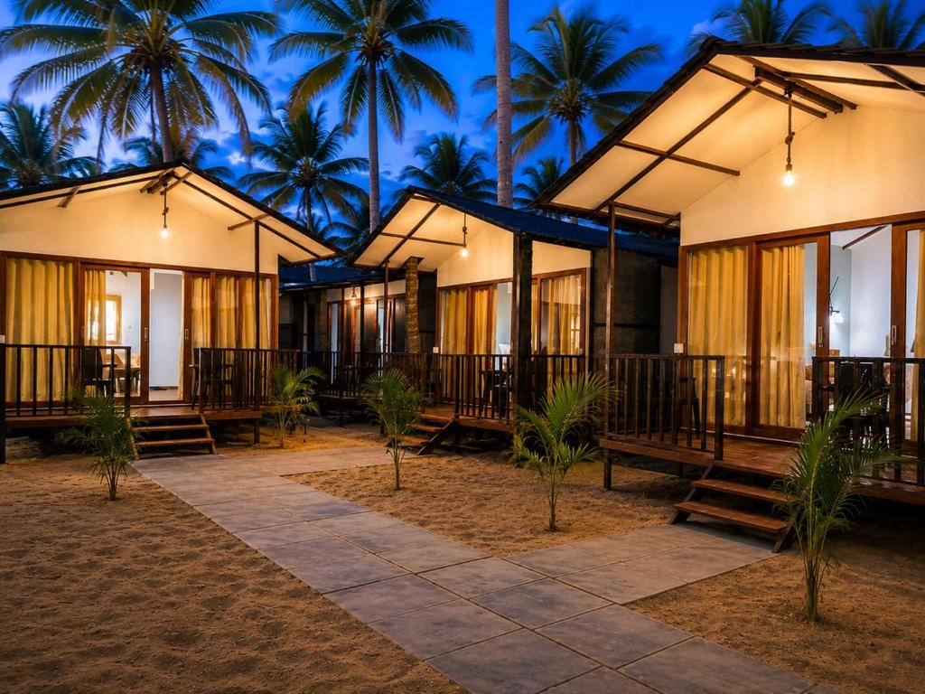 a row of houses with palm trees in the background at Seashell Cottages Palolem in Canacona