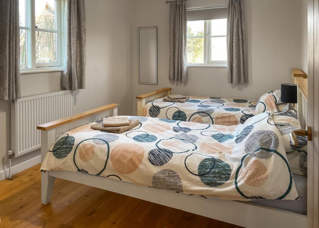 a bedroom with two beds and two windows at Oak Farm Lodges in Roydon