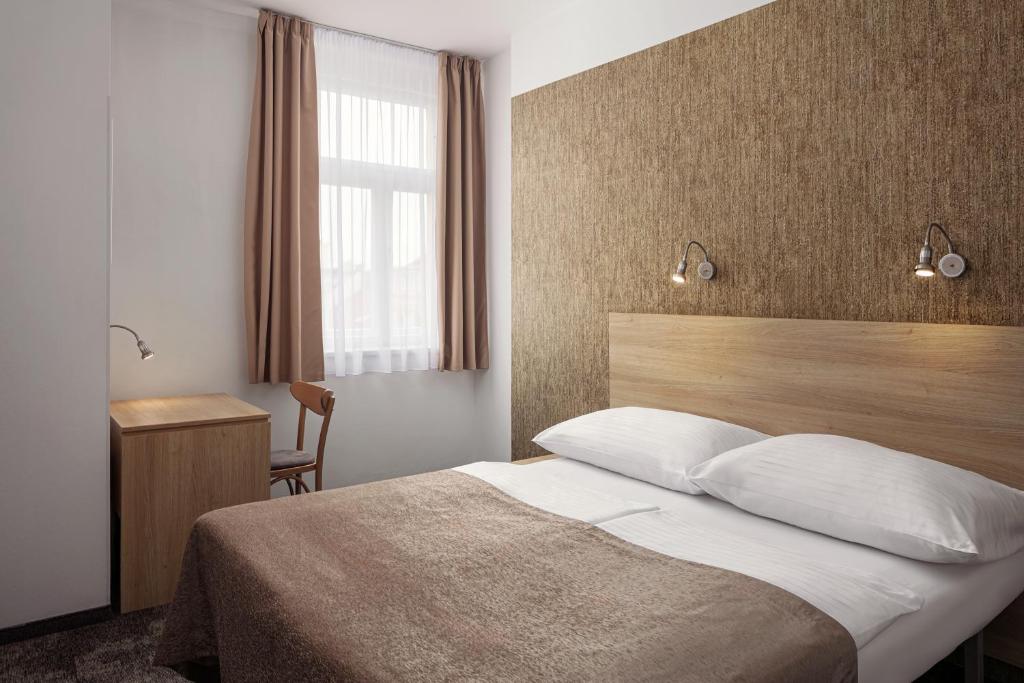 a bedroom with a bed and a desk and a window at Hotel Ambiance in Prague