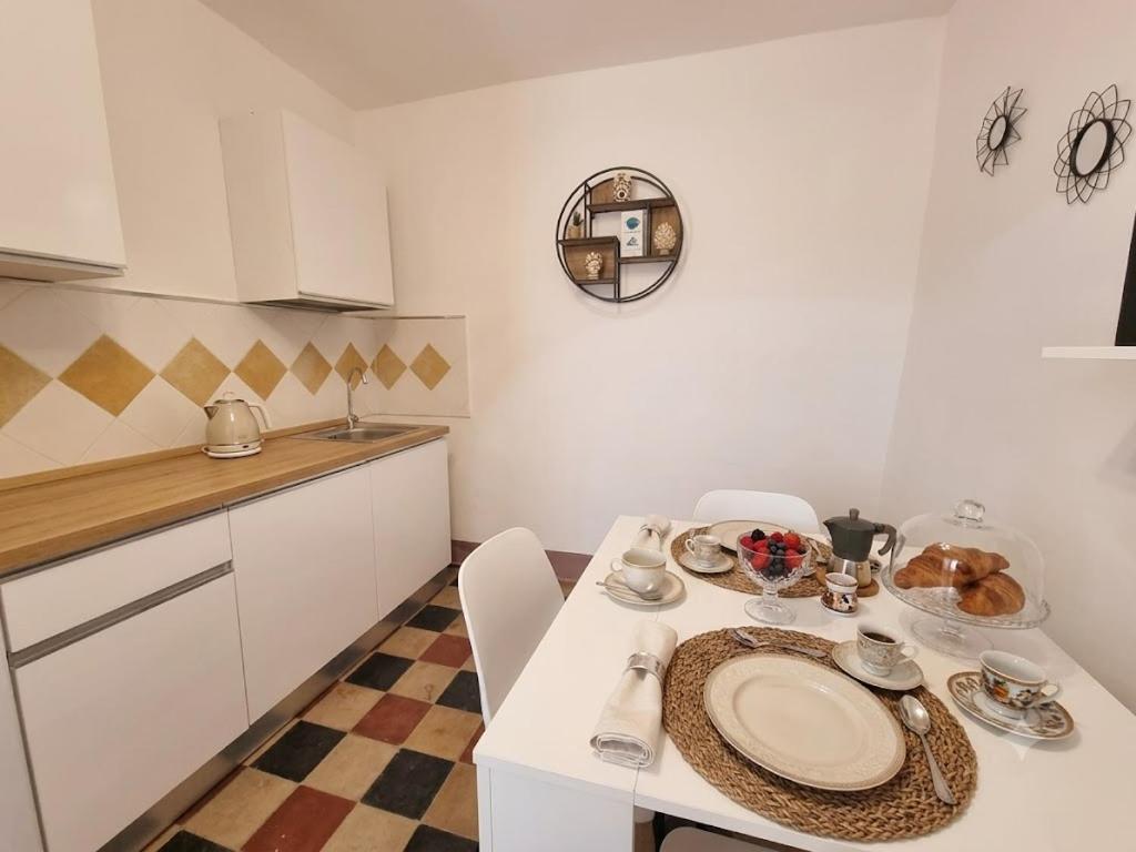 a white kitchen with a table with a plate of food on it at Antica Dimora Donna Emma in Carini