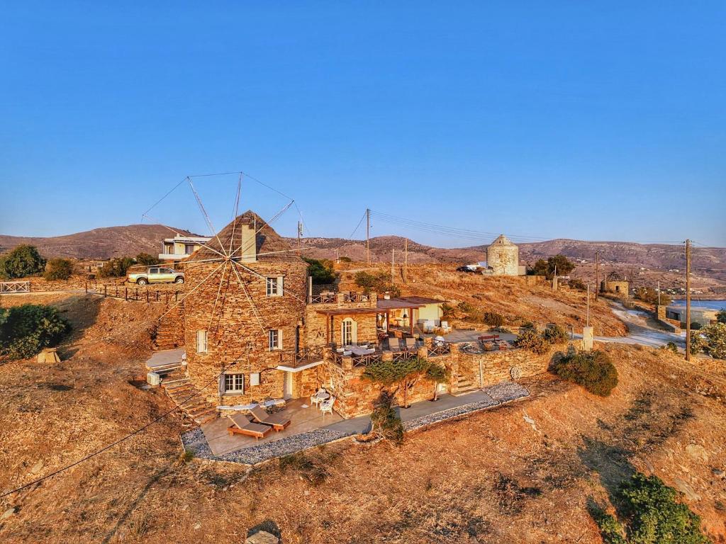 an old stone house on a hill with windmills at The Stone Windmill in Koundouros