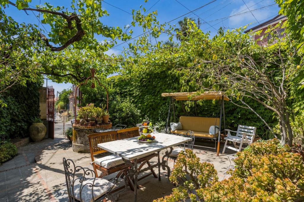 a patio with a table and chairs and trees at Casa Edera - Villa Storica in Viagrande