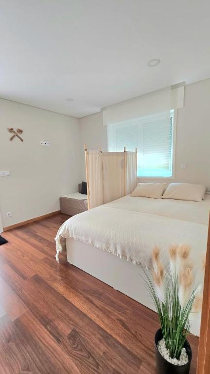 a bedroom with a white bed and a wooden floor at Vikings AL in Areosa