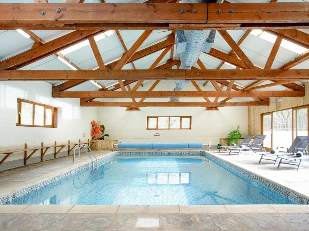 a pool in a building with a ceiling with beams at The Cider Barn - Hggl in Luton