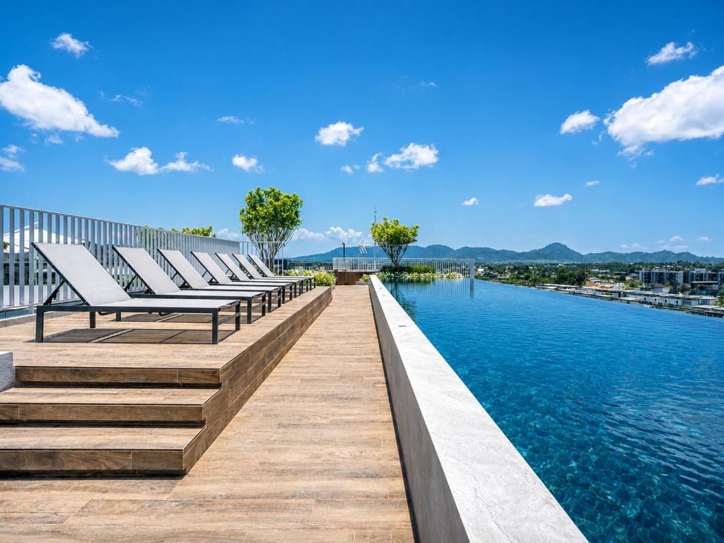 a row of benches on a boardwalk next to the water at Sky Park Laguna 2BR Condo with Balcony in Laguna Phuket