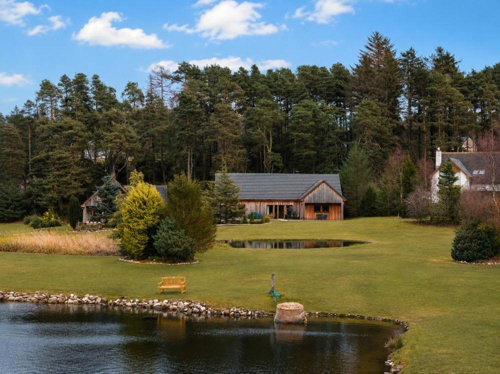 a house with a pond in front of it at Lakeside Lodge, Views, Hot Tub & Fully Accessible in Elgin