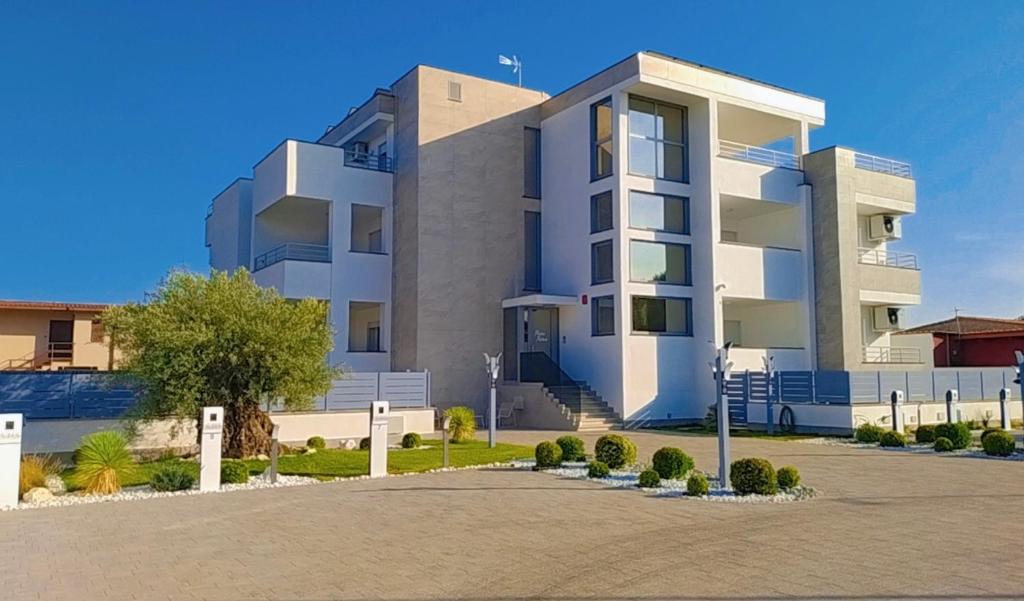a white apartment building with a parking lot at Pierre Palace in Isola Sacra