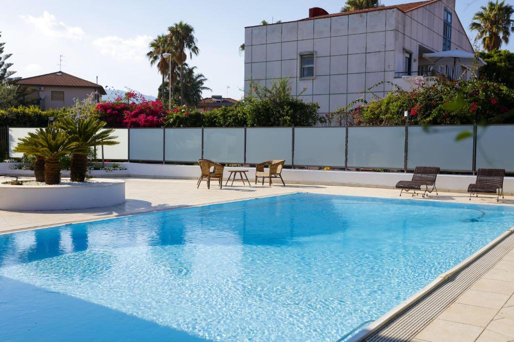 ein Schwimmbad mit Stühlen und einem Tisch neben einem Gebäude in der Unterkunft Path House by Wonderful Italy in Riposto