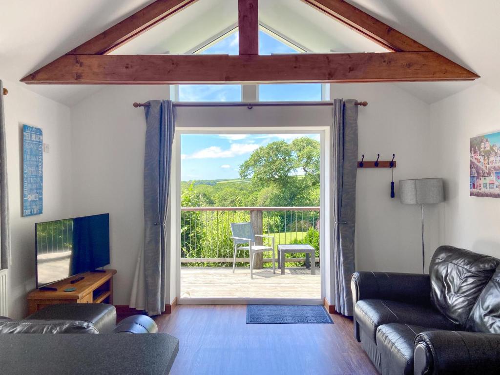a living room with a couch and a large window at Sunset in St Austell