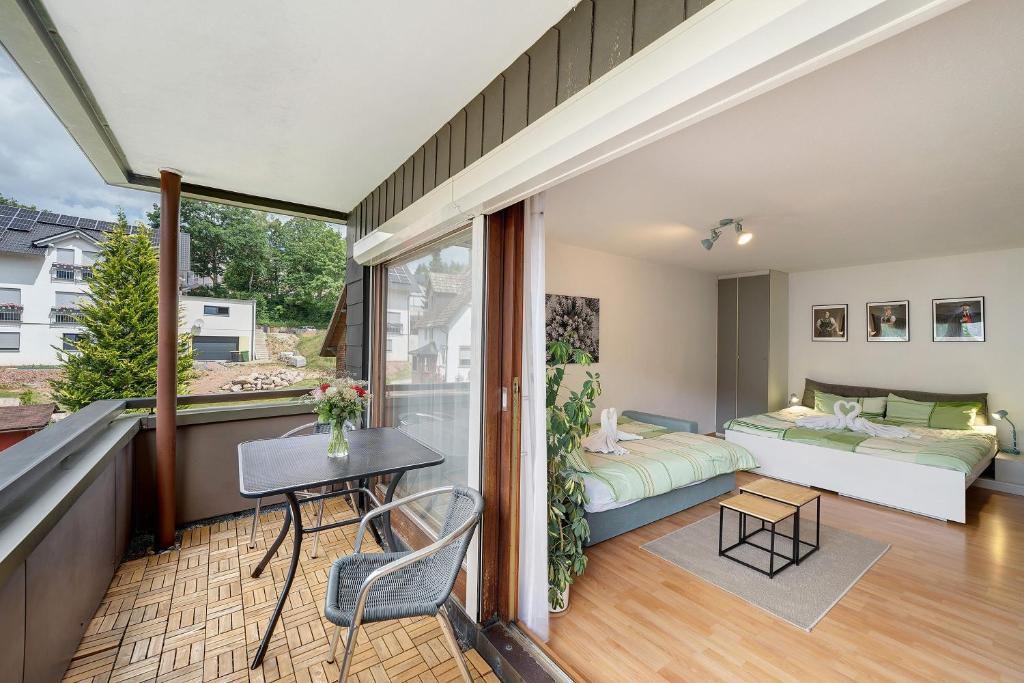 a room with a balcony with a bed and a couch at Schanzenblick mit Sauna und Pool in Schönwald