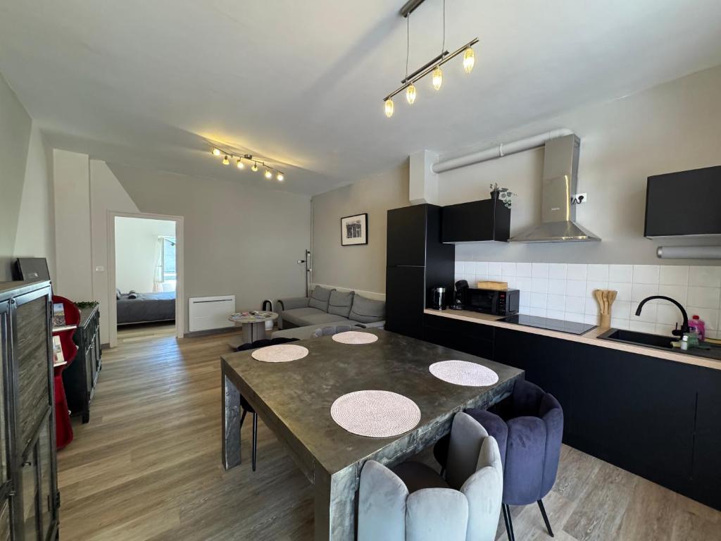 a living room with a table and a kitchen at Le Cosy Industriel in Le Puy-en-Velay