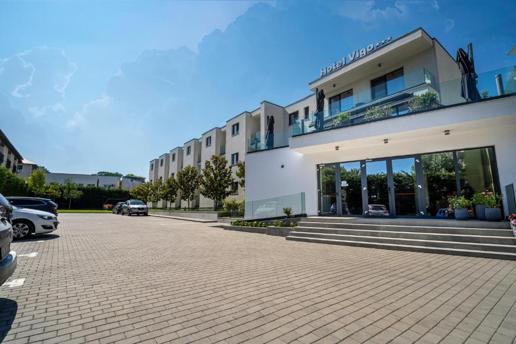 a building with cars parked in a parking lot at Hotel Vigo in Eforie Nord