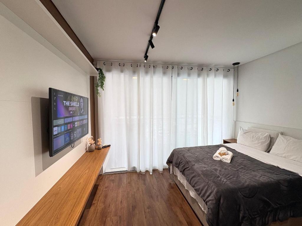 a bedroom with a bed and a large window at HLB_1006- Studio Completo com Vaga | Próx. GRU in Guarulhos