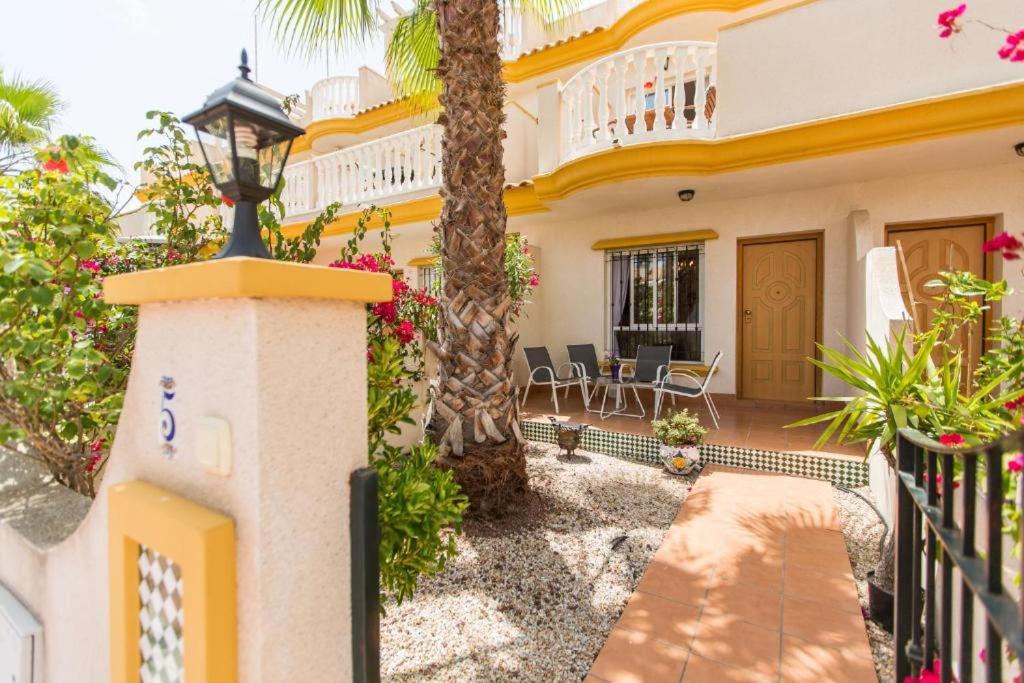 a villa with a palm tree and a house at Oriheula Costa Cabo Roig 5 in Playas de Orihuela