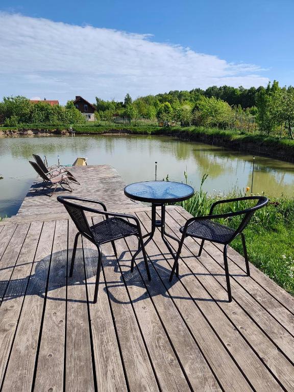 a table and two chairs on a dock with a lake at Zeigių apartamentai in Normantai