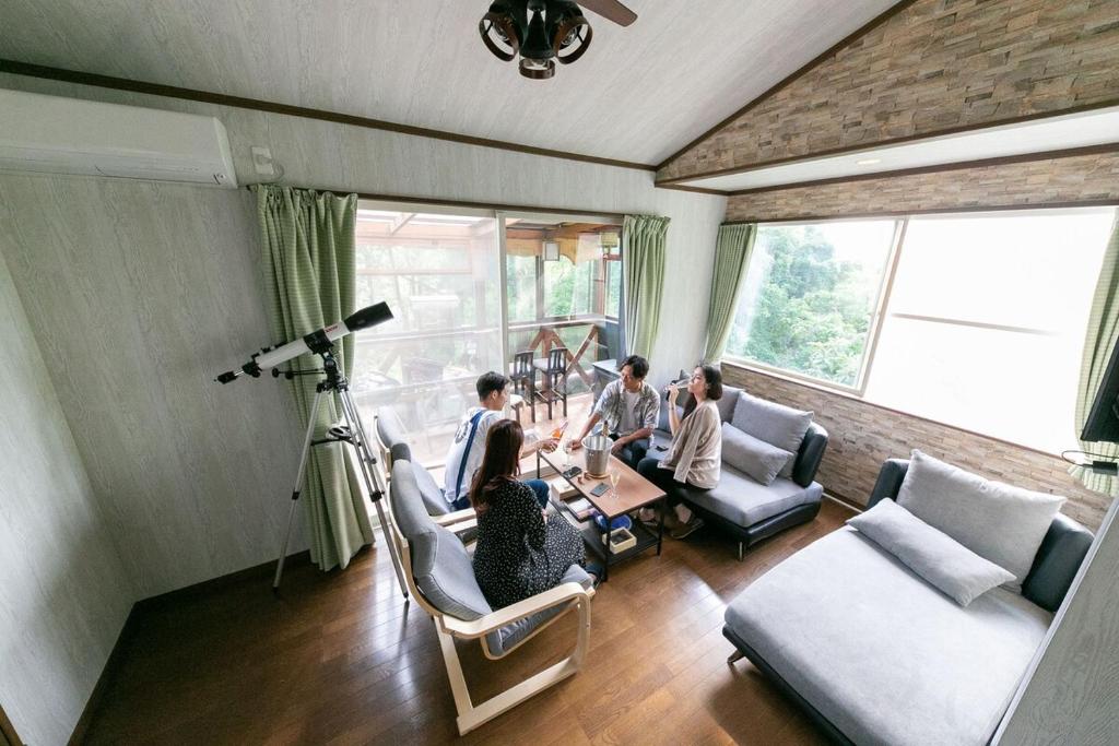 a group of people sitting around a table in a living room at コテージひだまり in Izunokuni