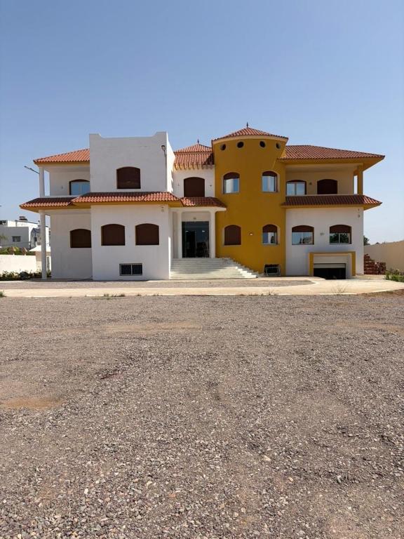 a large yellow and white house with a driveway at Dar Llama in Nador