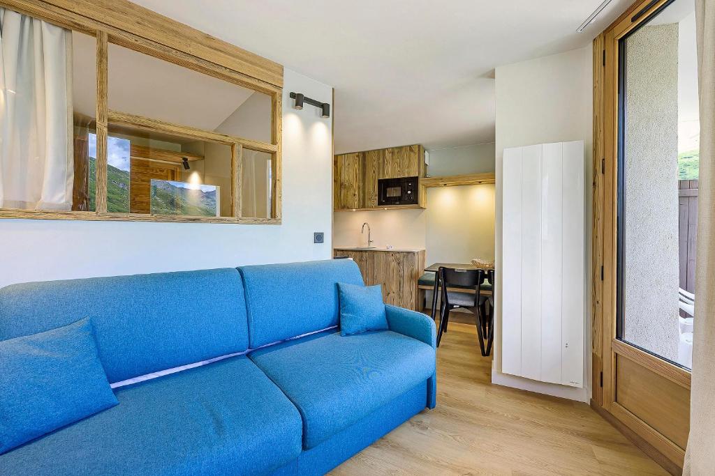 a blue couch in a living room with a kitchen at Appartement Le Panorama Des Pistes in Les Menuires