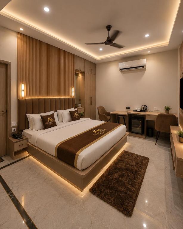a bedroom with a large bed with a desk and a desk at Atlantiis Suites Inn By Signature Stays Near Vishwanath Temple Rathyatra in Kakarmatha