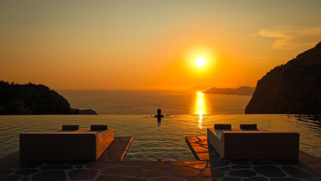 a person in a infinity pool watching the sunset at Klay Hotel Faralya Adults Only in Faralya