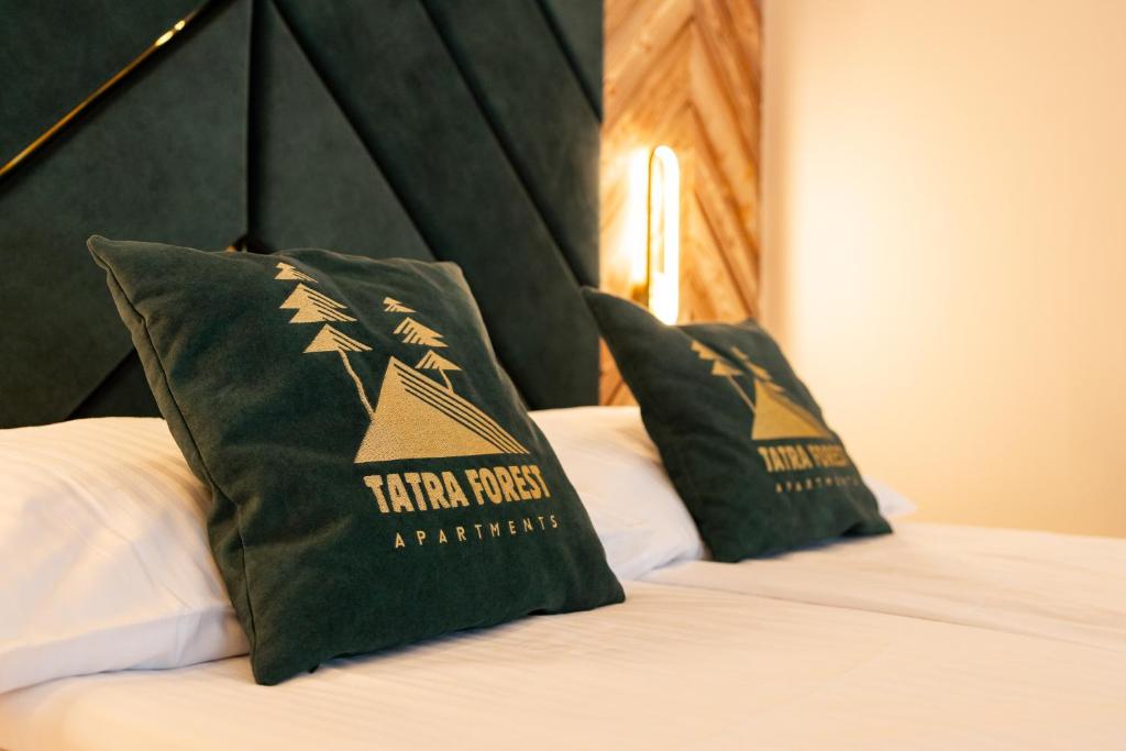 a bed with two green pillows on top of it at Tatra Forest Apartments in Zakopane