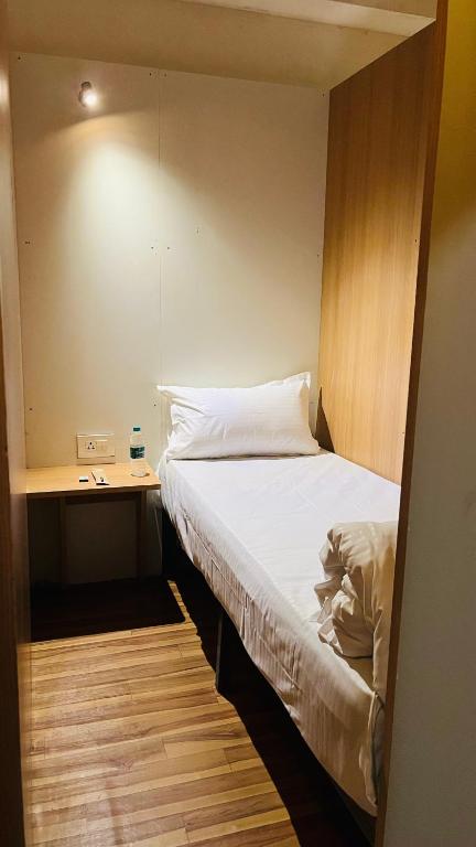 a small bedroom with a bed and a desk at Lowfare Hotels Bengaluru in Bangalore