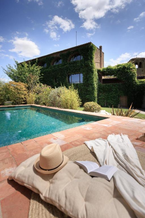 a hat sitting on a blanket next to a swimming pool at Encís d'Empordà -Adults Only- in Casavells