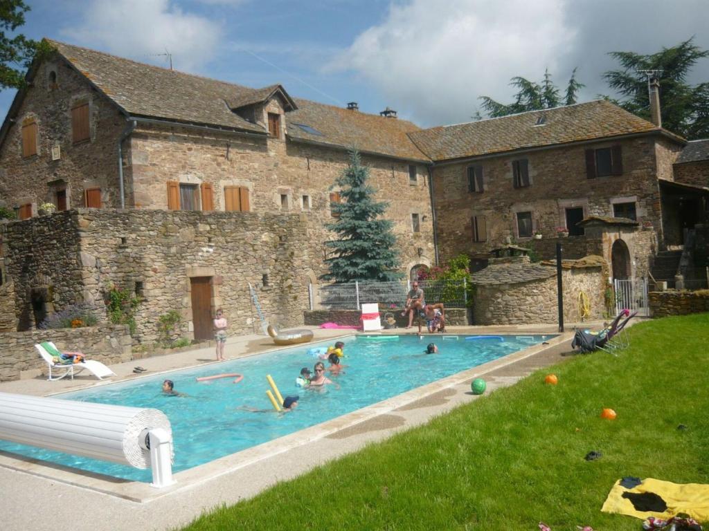 a group of people in a swimming pool in front of a building at Chambres D'hôtes Le Sahut in Castelnau-Pégayrols