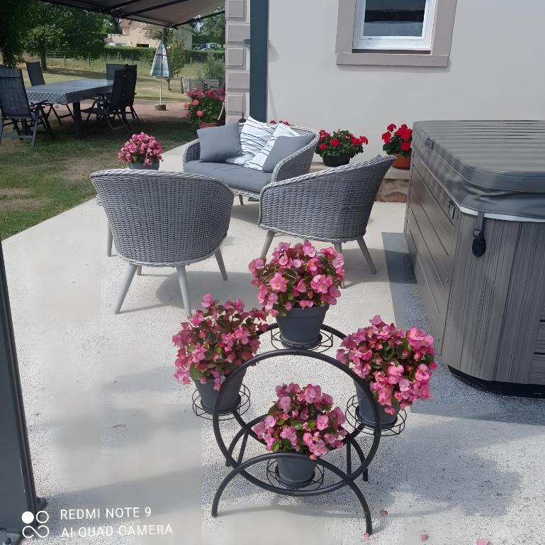 a patio with two chairs and flowers in pots at Entre Brionnais Et Bourbonnais in Montaigüet-en-Forez
