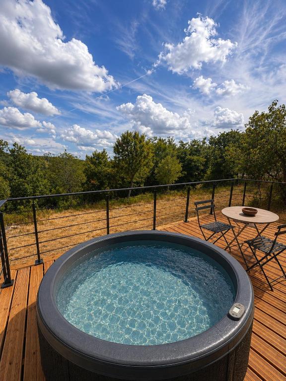a hot tub on a deck with a table and chairs at Lo Coustil in Saint-Martin-Labouval