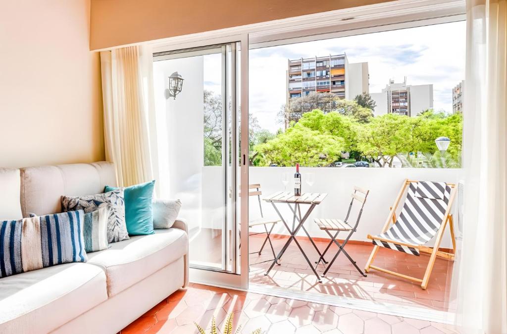 a living room with a couch and a sliding glass door at Apartamento Village Elvas in Vilamoura