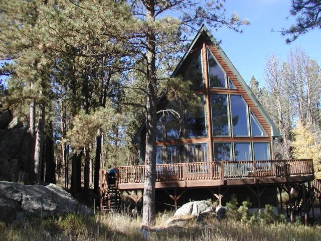 a large house with a large deck in the woods at ThunderHeart in Custer