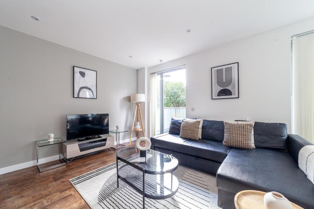 a living room with a black couch and a tv at Gorgeous 1 Bed Apartment in Poplar in Richmond upon Thames