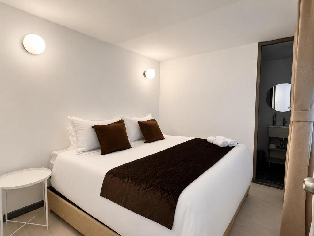 a bedroom with a large white bed with brown pillows at Zentio Hotel in Bogotá