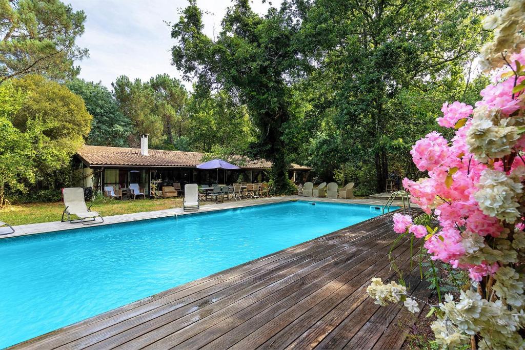 a swimming pool with a wooden deck and flowers at Maison de vacances Namasté in Mérignac
