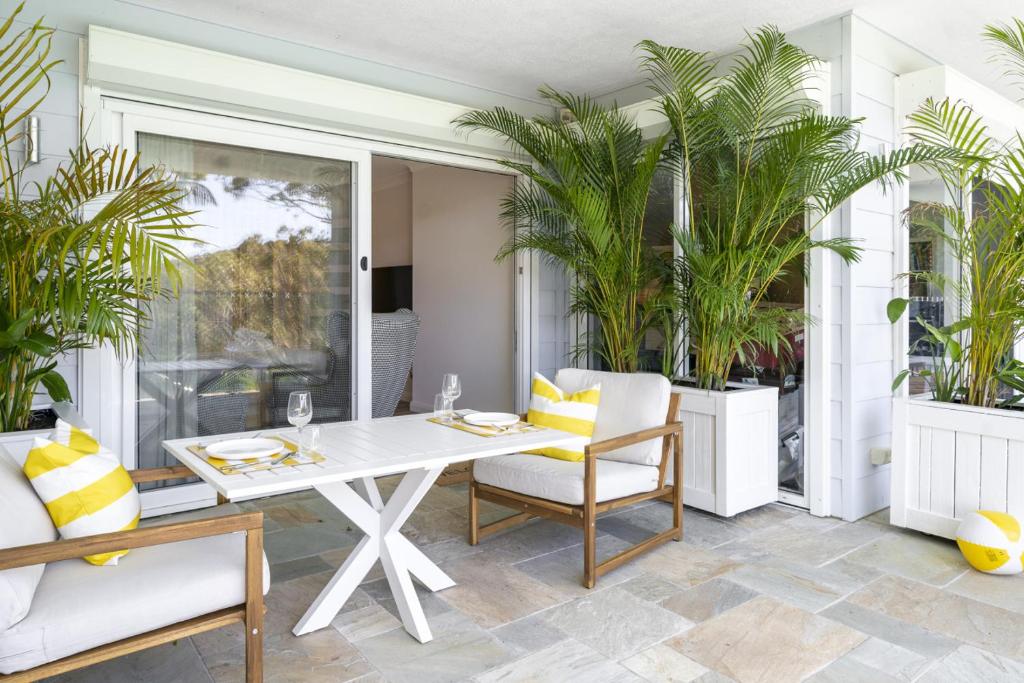 a dining room with a table and chairs and palm trees at Garigal Studio 1br Unit with Pool Access and EV Station in Forestville