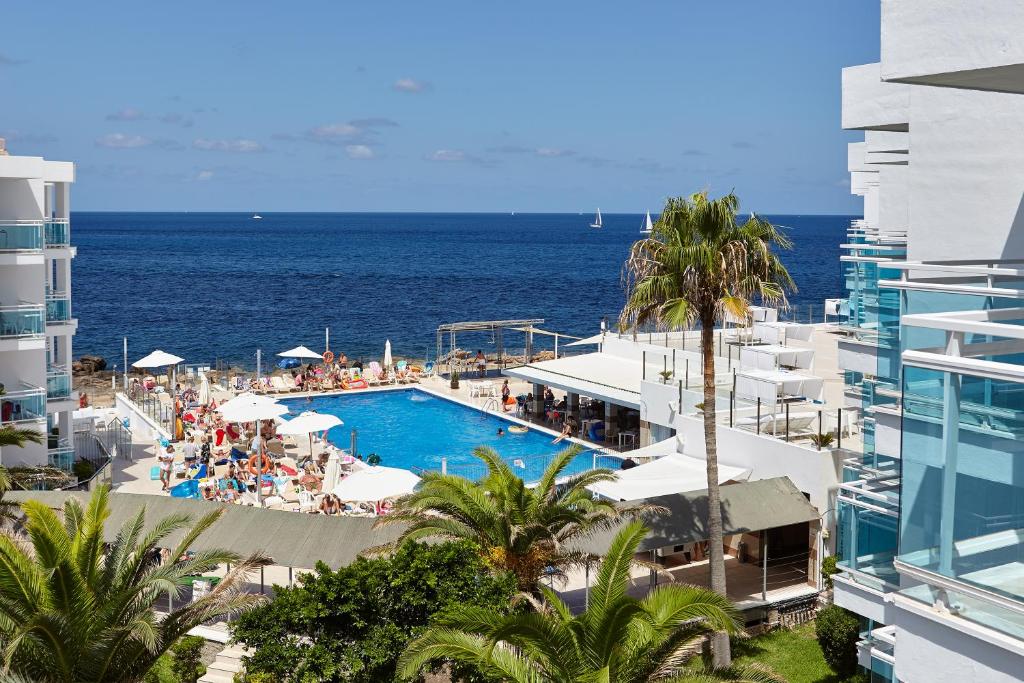 a view of a pool and the ocean from a building at Aparthotel Nereida in San Antonio Bay