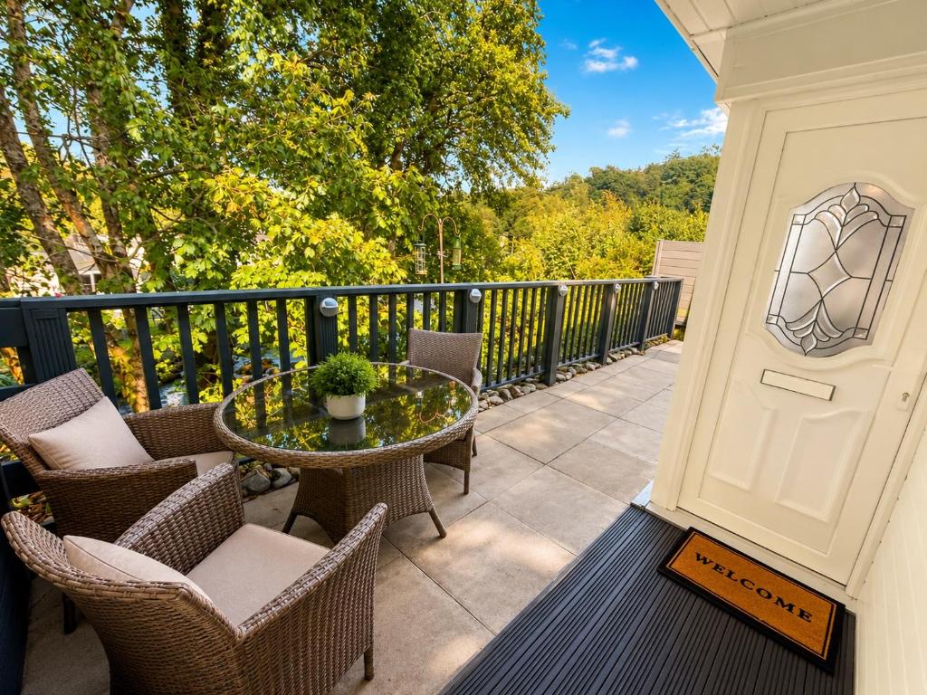 a patio with chairs and a table on a balcony at 18 river view chalet-Glan Gwna Holiday Park in Caernarfon